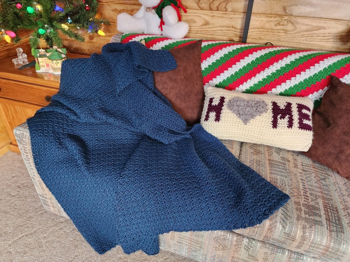 Crocheted afghans and pillows on a sofa near Christmas decorations