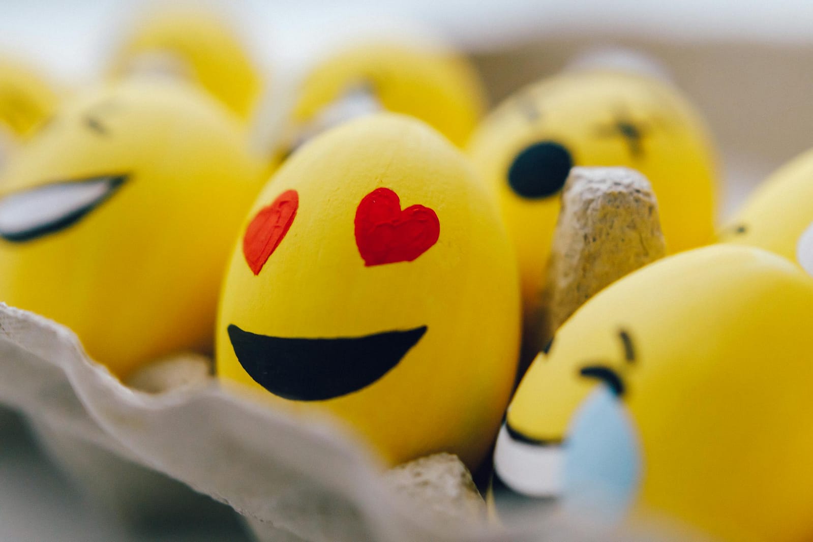 Bright yellow emoji Easter eggs with fun expressions in an egg carton. Perfect for festive decorations.