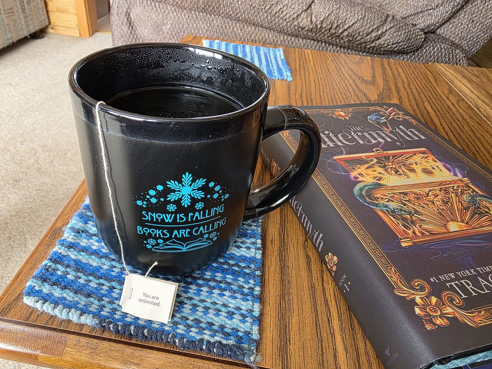 Mug with tea on coaster and books sitting beside it