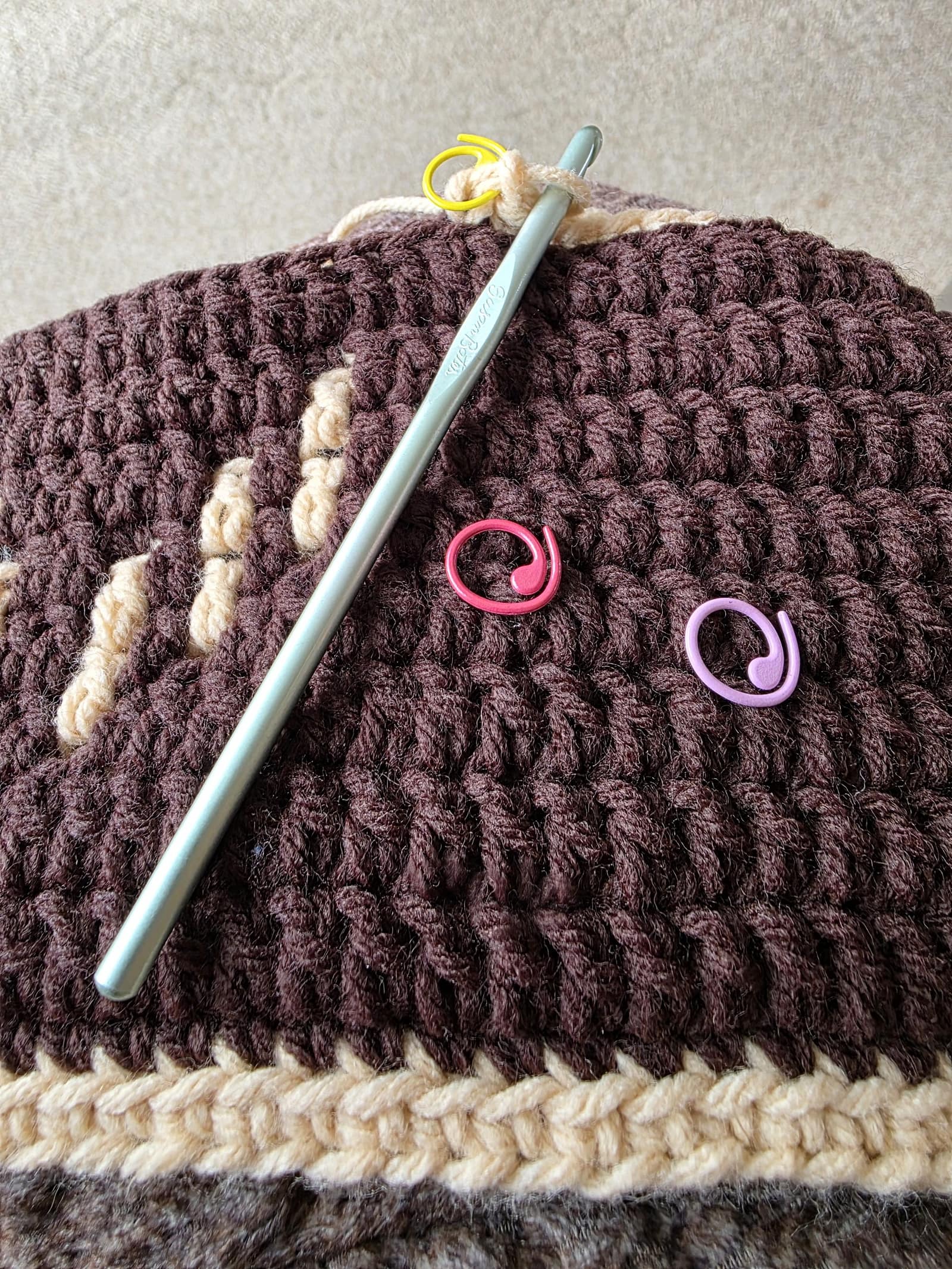 Section of crocheted afghan with crochet hook and stitch markers